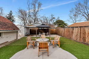 View of patio / terrace featuring an outbuilding, a gazebo, outdoor dining space, and fence