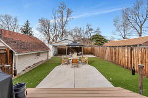 Wooden terrace with a gazebo, a yard, a patio, and a fenced backyard