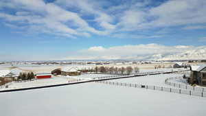 Yard covered in snow featuring fence and a mountain view