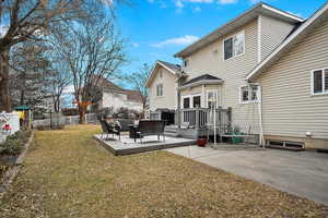 Rear view of property featuring a deck, a patio area, and a lawn