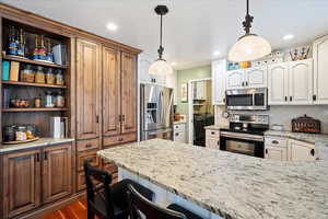 Kitchen with light stone counters, decorative light fixtures, and appliances with stainless steel finishes