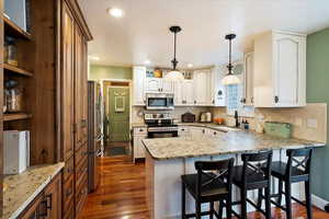 Kitchen featuring white cabinetry, stainless steel appliances, sink, and hanging light fixtures