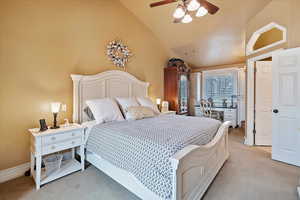 Master bedroom featuring ceiling fan, light colored carpet, and high vaulted ceiling