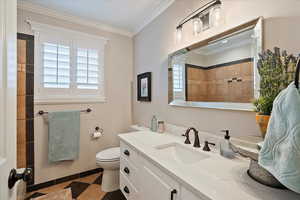 Main bathroom with crown molding, plenty of natural light, toilet, and vanity