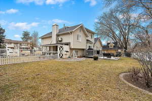 Rear view of property with a wooden deck, a lawn, and a patio