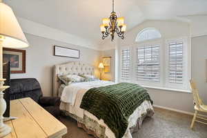 Bedroom with a notable chandelier, vaulted ceiling, and carpet flooring