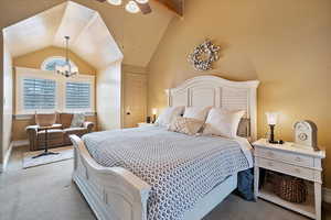 Master bedroom with light carpet, a textured ceiling, lofted ceiling with beams, and a chandelier