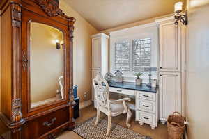 Master bedroom featuring built in desk, vaulted ceiling, and carpet flooring