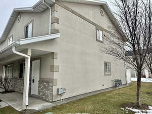 View of row-end townhome's exterior with stucco siding, a lawn, and a patio