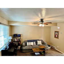 Comfortable and welcoming living room filled with natural light featuring a ceiling fan and plenty of space