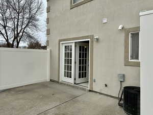 Private patio entrance with stucco siding, fence, central AC unit, and a access to dining and kitchen