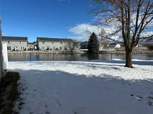 Yard layered in snow with a water view and a residential view