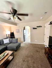 Light and spacious living room featuring arched walkways to kitchen, and light colored carpet