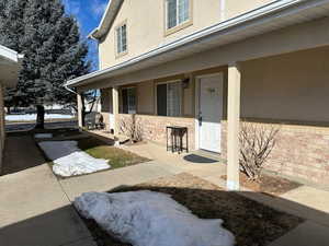 Entrance to townhome featuring covered porch and stucco siding