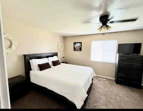 Carpeted light spacious bedroom with ceiling fan and baseboards