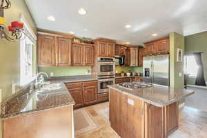 Kitchen with brown cabinetry, a center island, stainless steel appliances, a sink, and recessed lighting