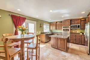 Kitchen with recessed lighting, appliances with stainless steel finishes, stone countertops, a kitchen island, and a sink