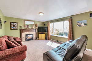 Living room with a tile fireplace, baseboards, and light colored carpet