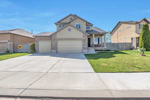 Traditional home with driveway, stucco siding, covered porch, fence, and a front yard