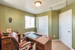 Home office featuring light carpet, attic access, and baseboards