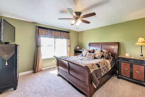 Bedroom featuring light carpet, visible vents, baseboards, and a ceiling fan