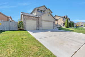 Traditional-style house featuring concrete driveway, an attached garage, fence, a residential view, and a front lawn