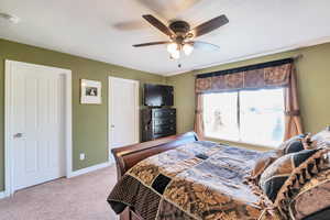 Bedroom featuring a ceiling fan, light colored carpet, and baseboards