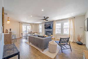 Living room with wood flooring, floor to ceiling fireplace feature.