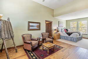 Living area featuring light wood-style floors, vaulted ceiling, ceiling fan, and baseboards