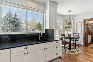 Kitchen featuring a chandelier, wood finished floors, a sink, white cabinetry, and pendant lighting