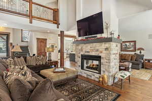 Living room with a fireplace, light wood-style flooring, and a towering ceiling