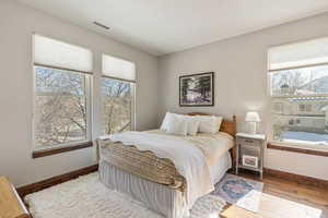 Bedroom with light wood-style flooring, visible vents, and baseboards