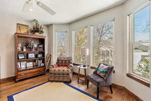 Sitting room featuring light wood-style flooring, baseboards, and ceiling fan