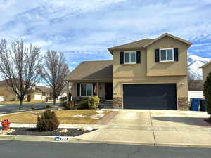 Traditional-style home with driveway, a shingled roof, stone siding, an attached garage, and stucco siding