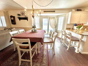 Dining area featuring dark wood-type flooring, a chandelier, a textured ceiling, and baseboards