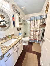 Full bath with toilet, shower / tub combo with curtain, a textured ceiling, and vanity