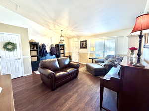 Living room with a textured ceiling, dark wood finished floors, and baseboards