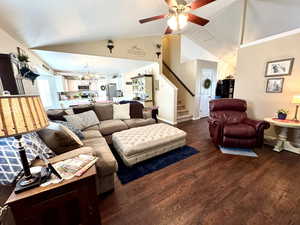 Great room with baseboards, dark wood finished floors, a ceiling fan, stairs, and vaulted ceiling