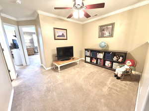 Living area with light colored carpet, visible vents, ornamental molding, a ceiling fan, and baseboards