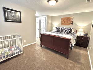 Bedroom 4 featuring visible vents, dark carpet, a textured ceiling, and baseboards