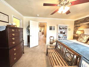 Primary Bedroom with a textured ceiling, wooden walls, ornamental molding, and light colored carpet