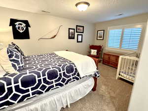 Bedroom 4 with carpet, visible vents, and a textured ceiling