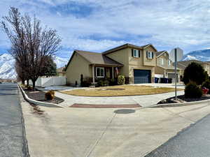 View of front of house featuring fence, a mountain view, concrete driveway, and stucco siding