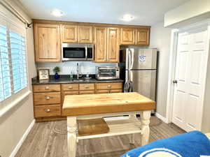 Kitchenette featuring a toaster, appliances with stainless steel finishes, brown cabinets, wood finished floors, and a sink. microwave and refrigerator included in the sale.