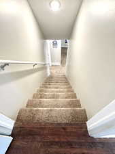 Staircase going to the basement with carpet flooring and a textured ceiling