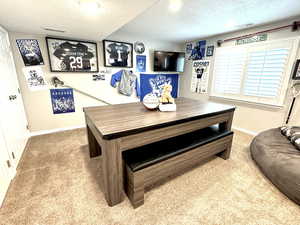 Carpeted game/dining area featuring a textured ceiling, visible vents, and baseboards