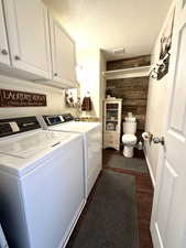 Laundry room featuring a textured ceiling, wooden walls, visible vents, independent washer and dryer, and dark wood finished floors