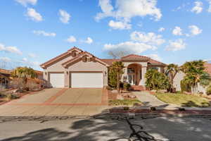 Mediterranean / spanish home featuring driveway, an attached garage, a tiled roof, and stucco siding