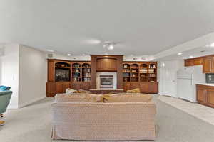 Living area featuring a fireplace with raised hearth, light carpet, and a textured ceiling