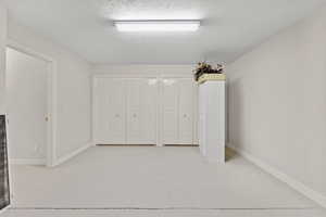 Interior space featuring multiple closets, finished concrete floors, baseboards, and a textured ceiling